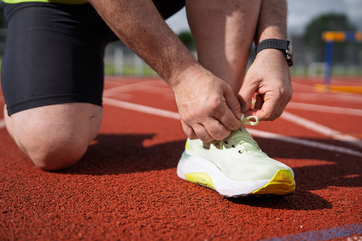 Runner tying shoelaces on athletic track getting ready