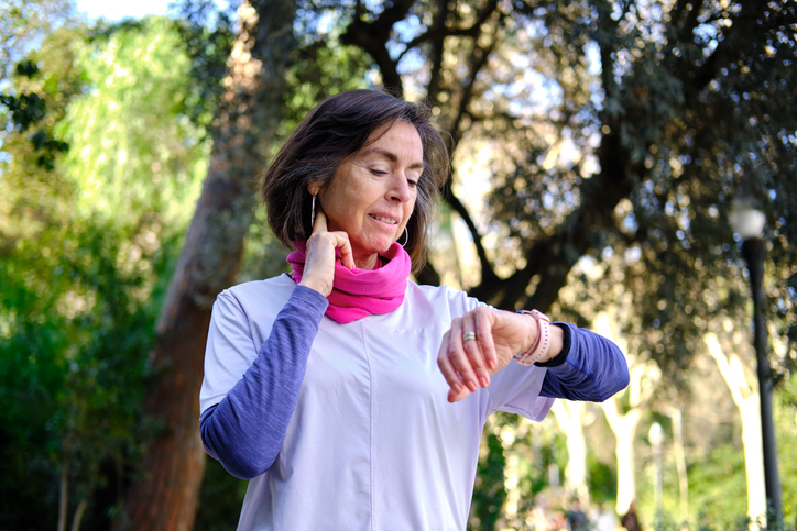 Mature woman checking pulse and smartwatch in park