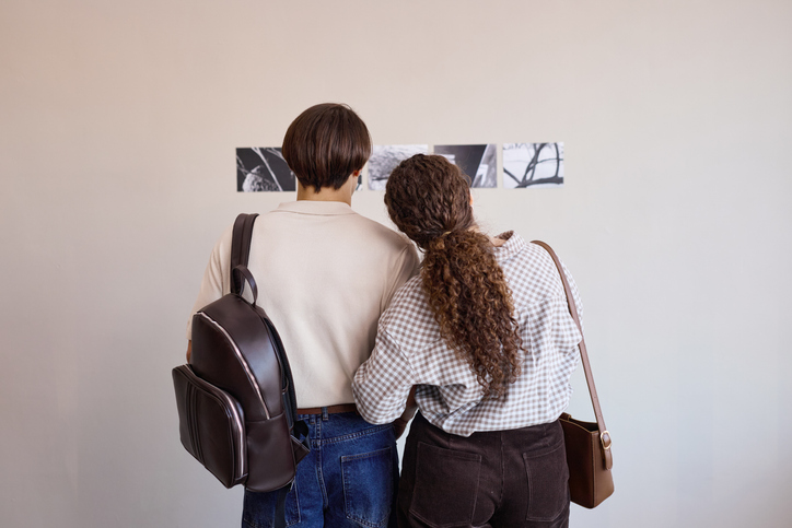 Young Adult Man and Young Adult Woman Observing Artworks in Gallery Setting