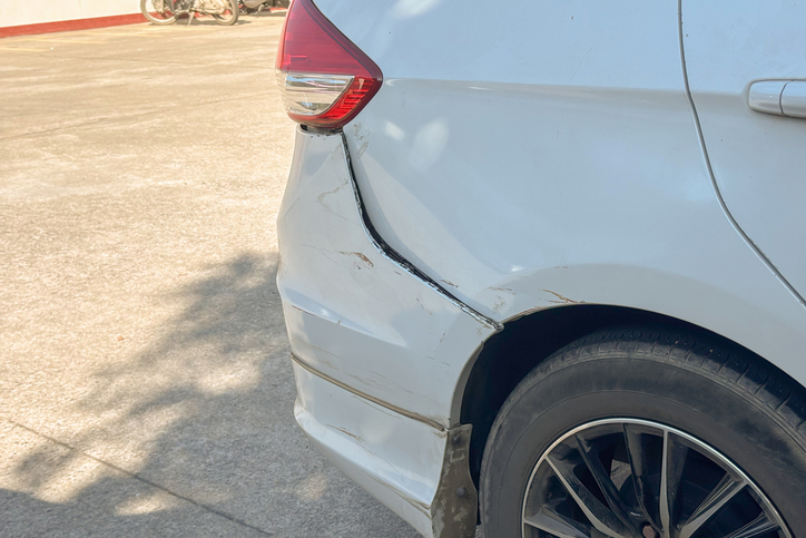 Rear bumper damage on a white car from a collision, car accident insurance concept