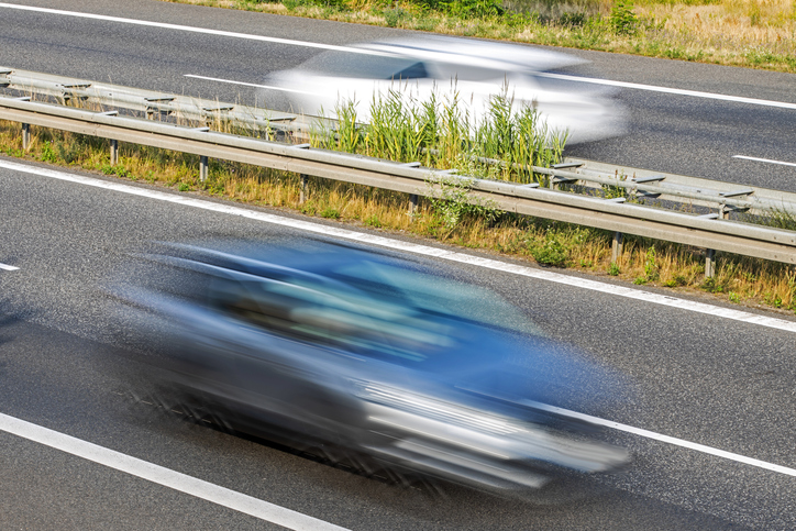 Two fast cars in different directions on a country road