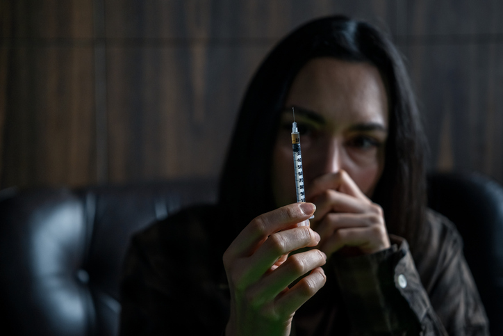 Addicted woman With Syringe in Dark Scene