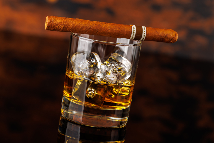 Glass of whiskey with ice and cigar