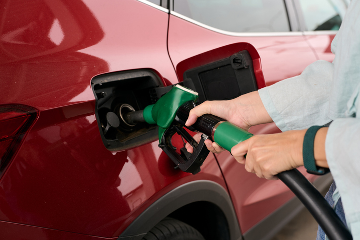 Woman refueling car with gasoline nozzle due to oil price crisis