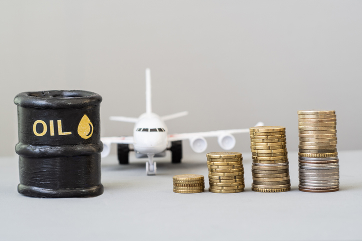 Oil barrel with an airplane and growing stacks of coins. Fuel Price Rising