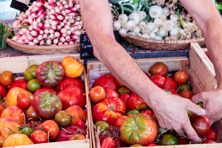 Farmer selling fresh heirloom tomatoes at market stall