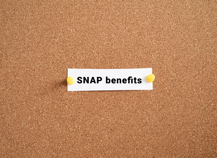 SNAP benefits label note pinned on cork bulletin board. USA federal food assistance program policy concept