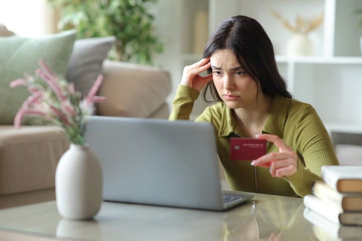 Worried young woman paying online at home
