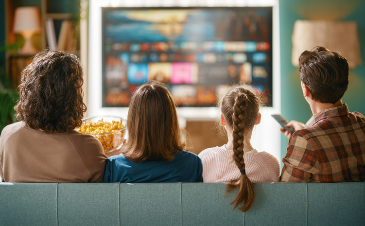 Happy Family Watching Television Together On Couch at Home with Popcorn