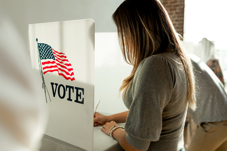 Woman voting in a booth privacy participation decision.
