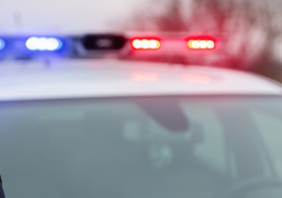 Police officer standing by patrol car with flashing lights