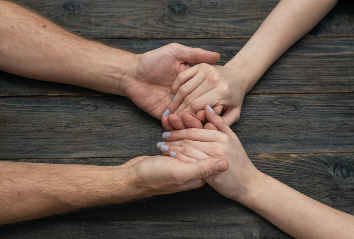 Loving man woman couple holding hands on dark wooden background.