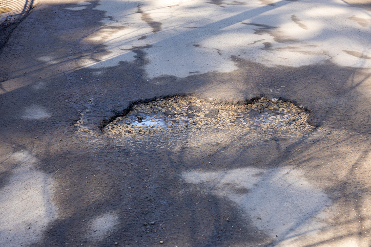 Asphalt pothole with puddle and shadows. High quality photo
