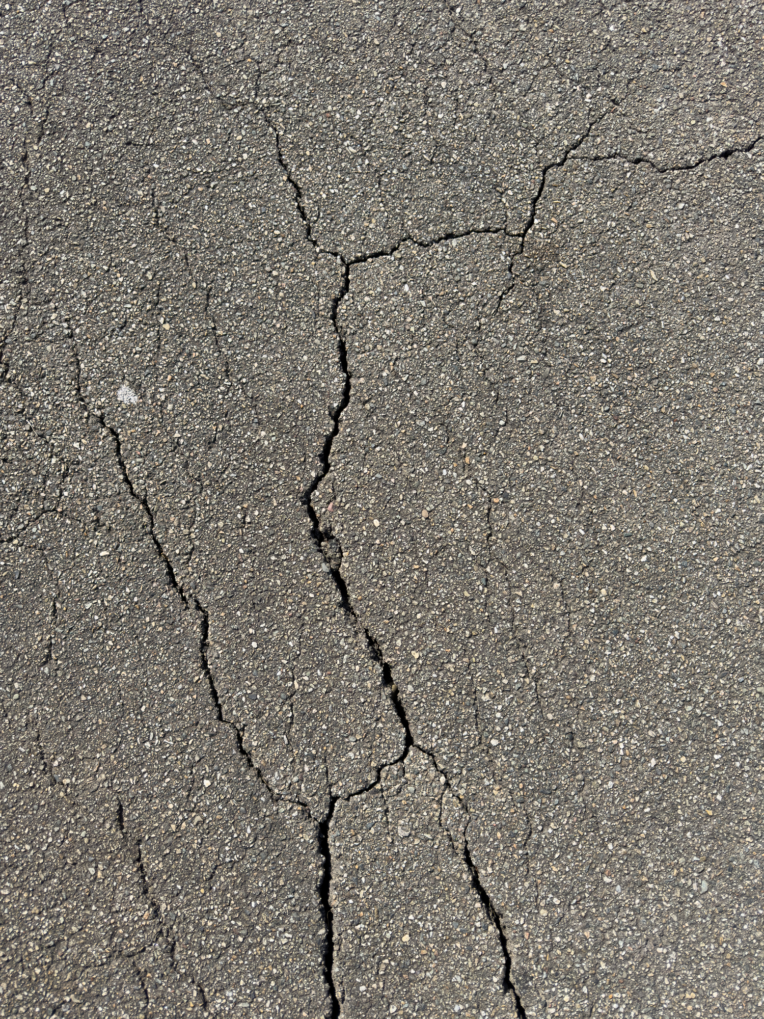 Cracks in dark gray asphalt pavement