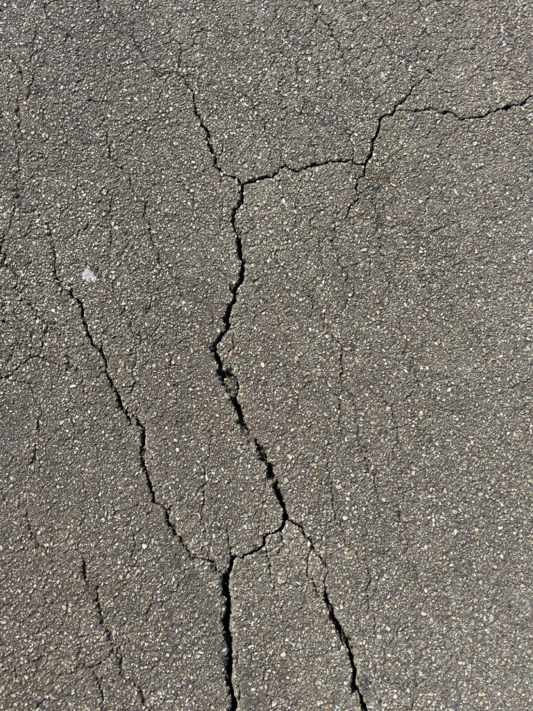 Cracks in dark gray asphalt pavement
