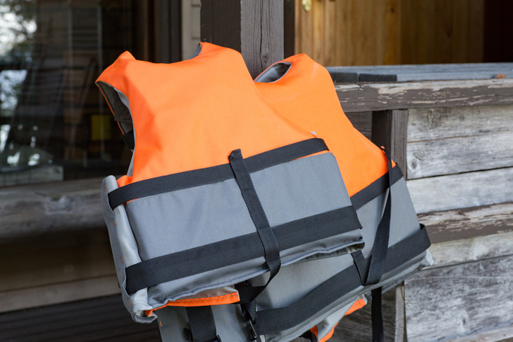 Orange and gray life jackets placed on an outdoor terrace while waiting for a summer boating trip. Bright daylight creates a fresh and relaxed outdoor atmosphere.
