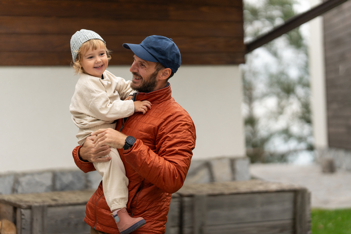 Loving father holding smiling toddler daughter outdoors