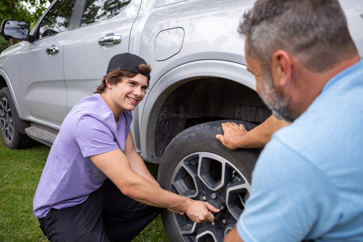 Father taught his teenage son how to change a car tire