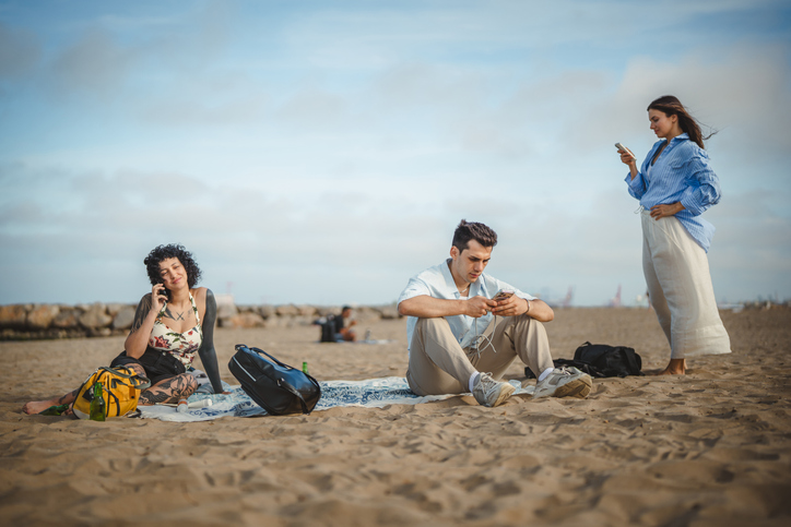 Young people addictive using smart phones on sandy beach