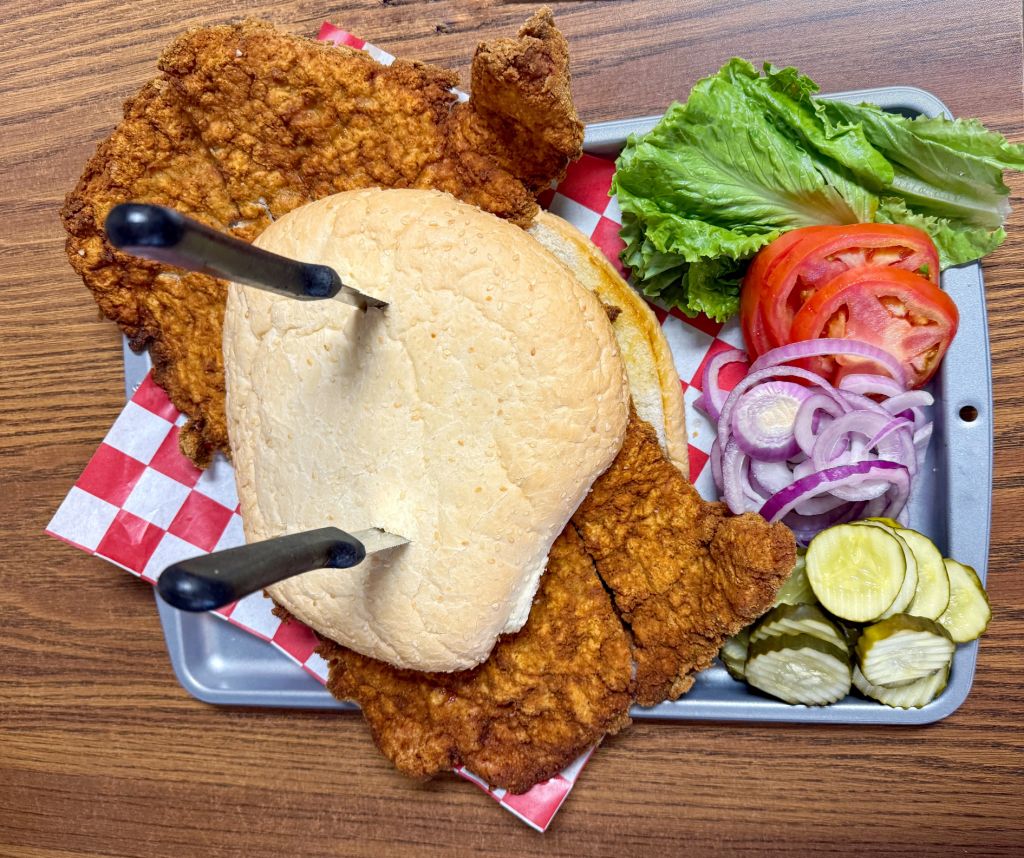 Massive breaded pork tenderloin sandwich with toppings in Iowa, USA