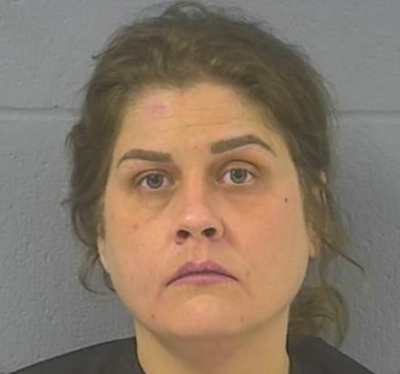 Mugshot-style portrait of a middle-aged woman with dark hair and a serious expression.
