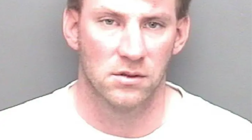 Headshot of a middle-aged man with a serious expression on a gray background.
