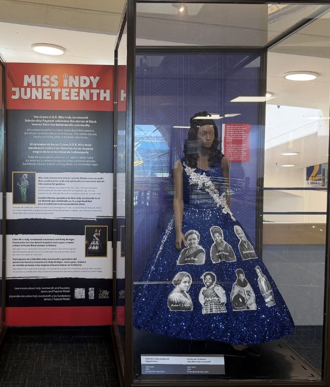 A display case featuring a blue sequined dress with portraits of Black women, accompanied by text about "Miss Juneteenth" and its significance.