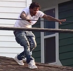 A person jumping from a roof onto a lower roof below.