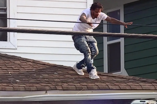 A person jumping from a roof onto a lower roof below.