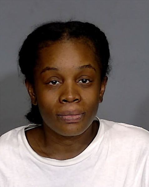 A portrait of a serious-looking African American woman with short dark hair wearing a white shirt against a gray background.