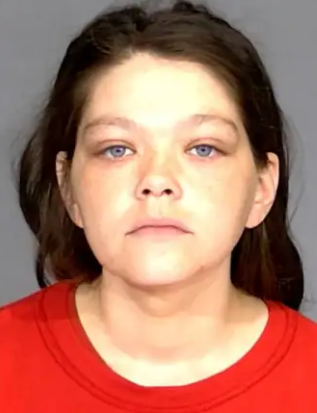 A young person with dark hair and blue eyes wearing a red shirt, looking directly at the camera with a serious expression.