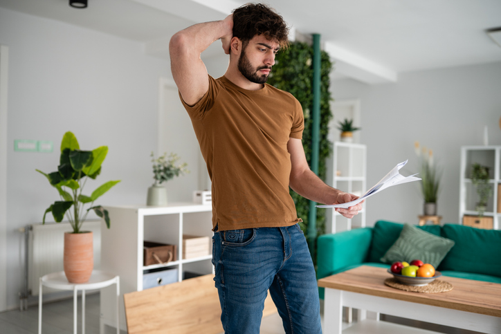 Young man stressing over financial problems at home