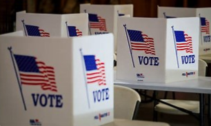 Voting booths with American flags and "VOTE" signs in a polling place.