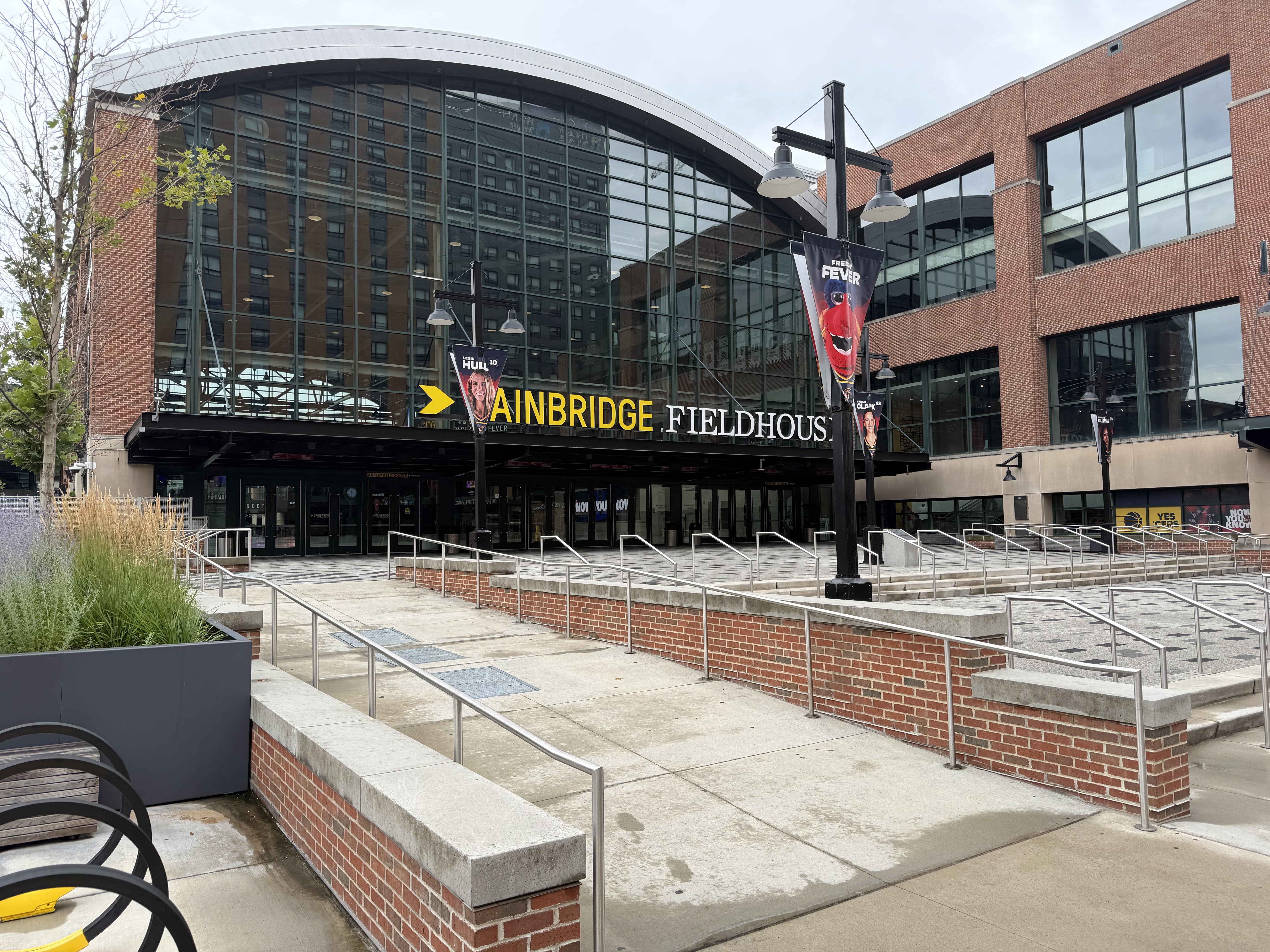 Exterior of the Ainbridge Fieldhouse, a large brick and glass sports arena with signage and steps leading to the entrance.