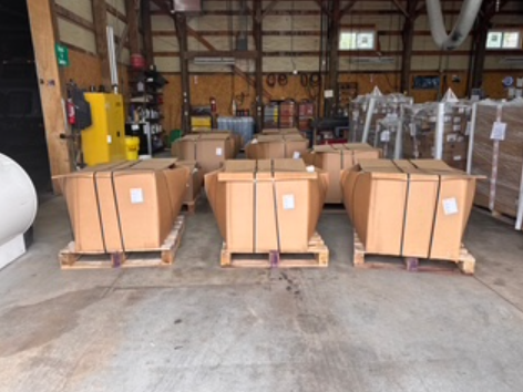 Warehouse interior with stacks of cardboard boxes on pallets, some with labels visible.
