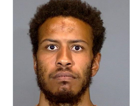 Headshot of a man with curly dark hair and a beard, looking directly at the camera with a serious expression.