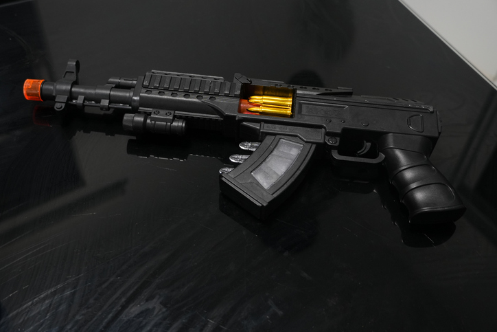 A black toy replica of an AK-47 rifle lying on a black surface