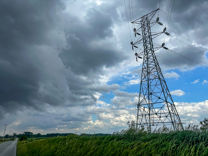 Rural scene of dark storm clouds by an electricity transmission pylon