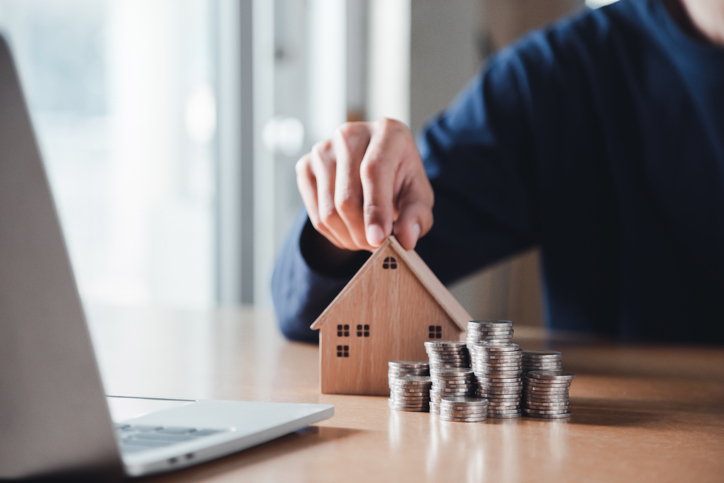 Man hand holding coin on wood table. Save money and financial investment and saving money for buying house, financial plan home loan concept.