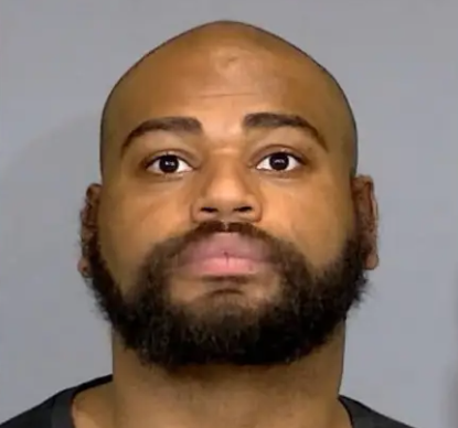 Headshot of a bald Black man with a beard wearing a black shirt.
