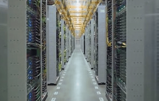 A long corridor filled with rows of computer servers and networking equipment in a data center.