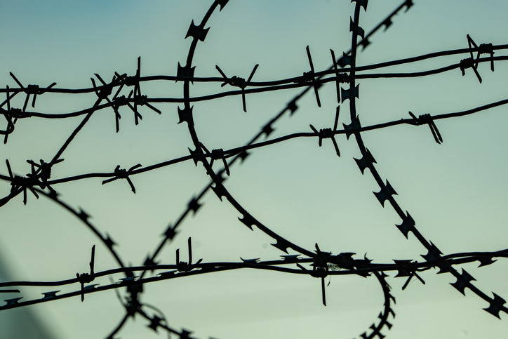 Tangled razor and barbed wire creating a strong barrier against a light sky