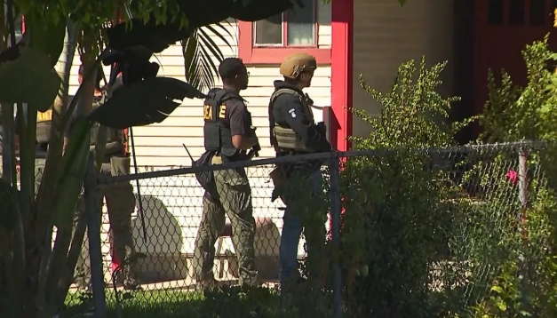 Two law enforcement officers standing in a fenced yard at night.