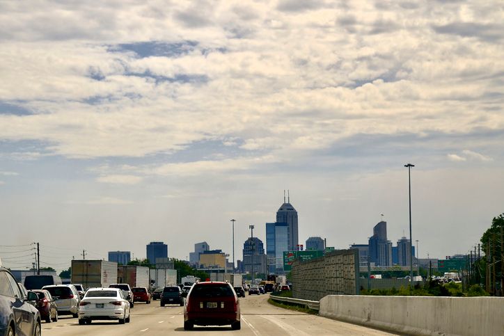 Evening Traffic moves into Indianapolis with city skyline visible on a cloudy day during midday