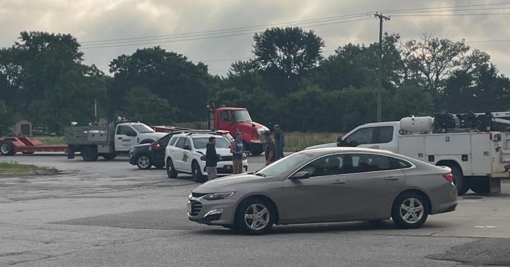A rainy day at a vehicle repair shop, with various cars, trucks, and utility vehicles parked in the lot.
