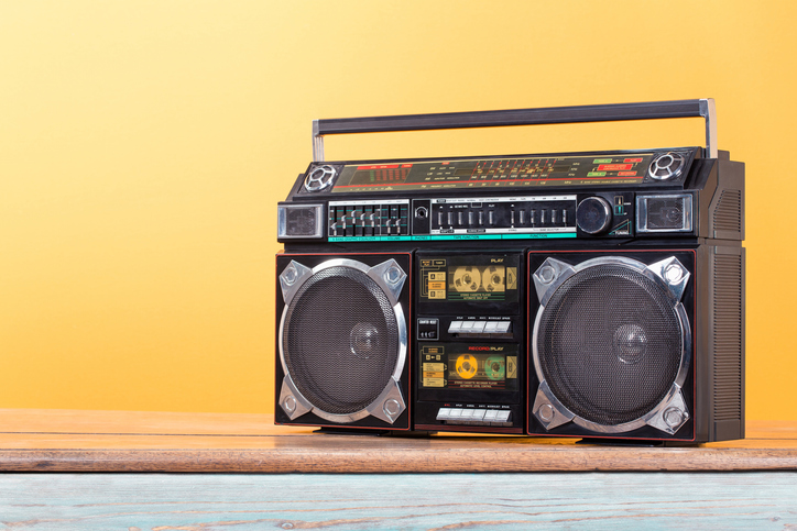Boombox radio stereo cassette recorder on vintage oak table front yellow background. Retro old style filtered photo