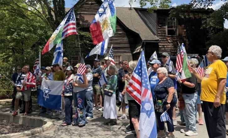 A crowd of people holding American and Israeli flags, gathered for what appears to be a political or patriotic rally or demonstration.