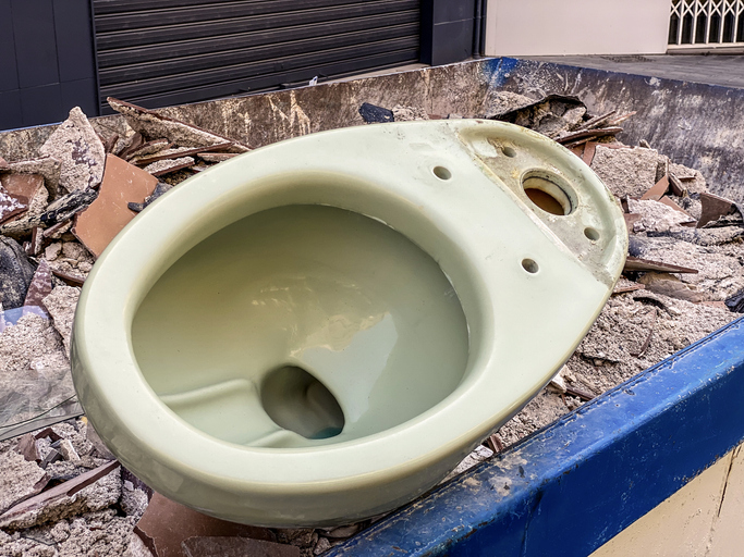 Vintage toilet bowl thrown inside garbage container