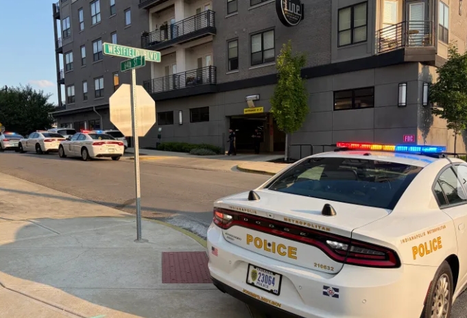 A police car parked on a city street, with a building and street sign visible in the background.