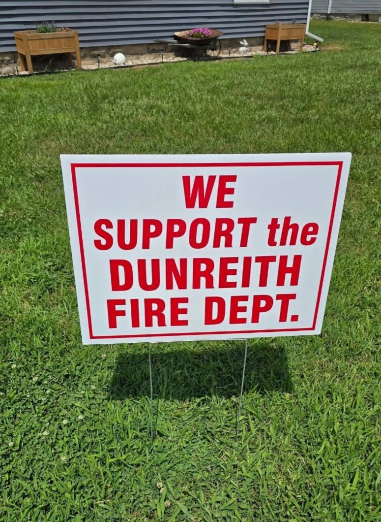 A sign in a grassy yard that reads "WE SUPPORT the DUNREITH FIRE DEPT.
